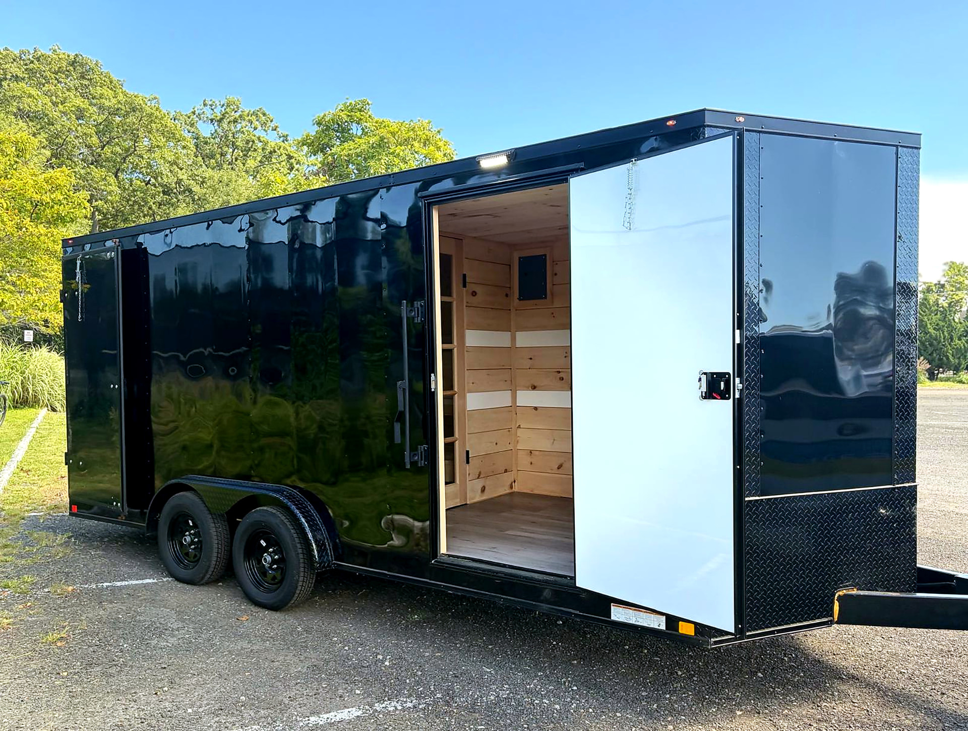 Black Nomad mobile sauna trailer parked outdoors with its side door open