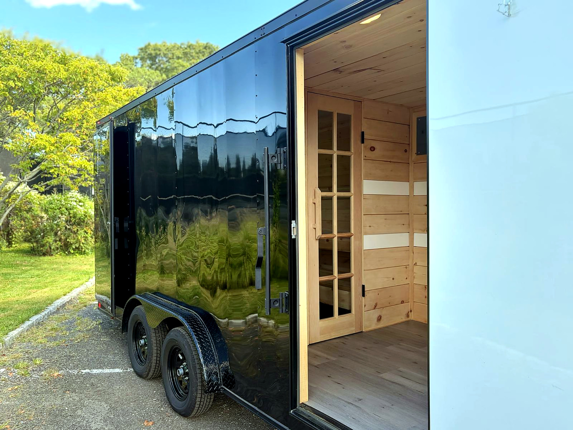 Side view of the black mobile sauna trailer showing its open entrance and cedar-lined changing area